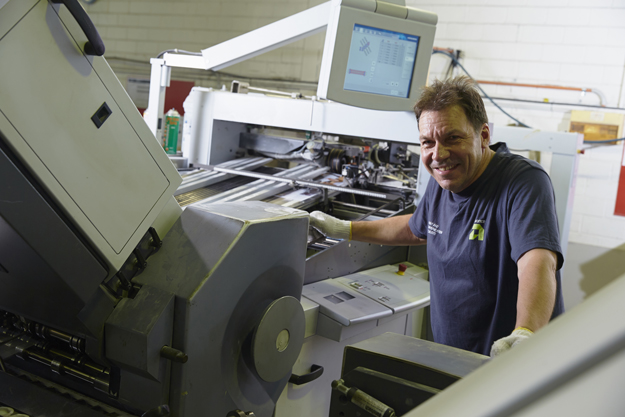 Advance Press staff member running folding machine at Perth factory
